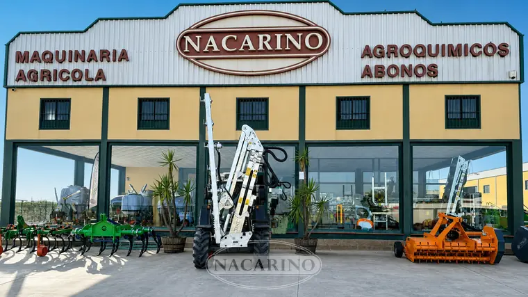 Tractor con barra de poda de discos articulada, delante de la nave de Nacarino en Aceuchal