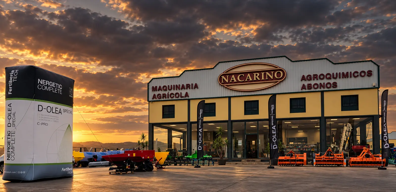 Fachada de Agrícola Nacarino al atardecer, con el hinchable de Fertiberia y abonadoras y gradas expuestas en la campa