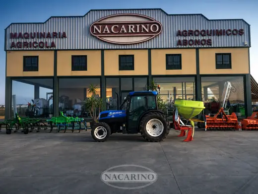 Tractor azul con abonadora delante de la nave de Nacarino en Aceuchal