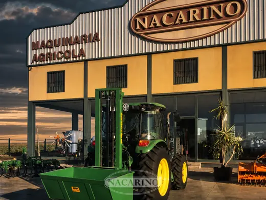 Tractor con elevador de mástil y cazo delante de la nave de Nacarino en Aceuchal
