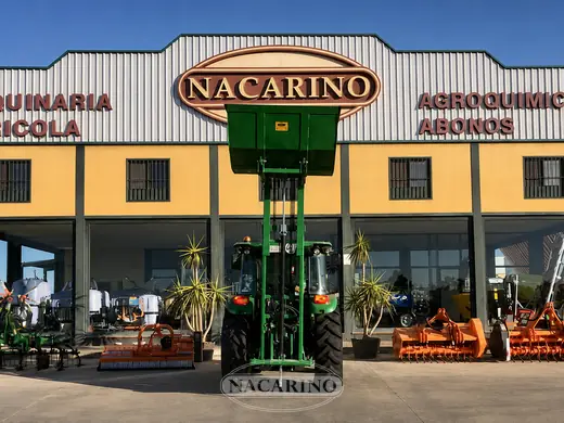 Tractor con tolva elevadora delante de la nave de Nacarino en Aceuchal