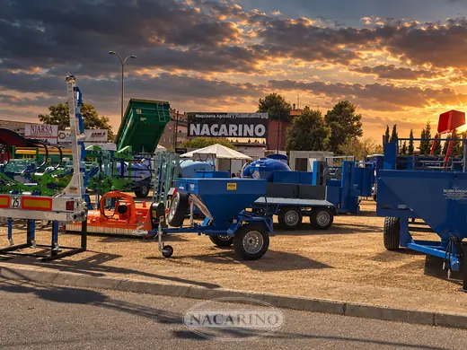 Campa de exposición de Nacarino al atardecer, con tractor y aperos delante de la nave