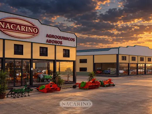 Las dos naves de Nacarino al atardecer, con cultivador, trituradoras y fresadora expuestos delante