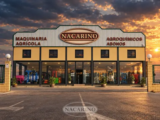 Fachada de la exposición de Nacarino al atardecer, con la maquinaria vista a través de los cristales