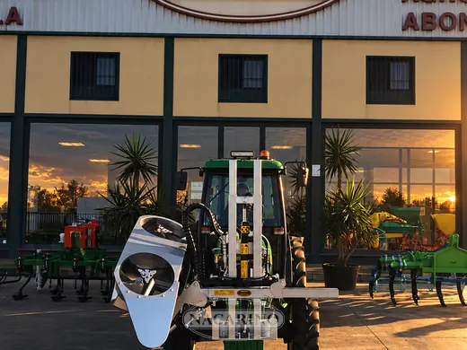 Tractor con apero frontal montado en bastidor deslizante, delante de la nave de Nacarino en Aceuchal