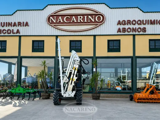 Tractor con barra de poda y aperos delante de la nave de Nacarino en Aceuchal