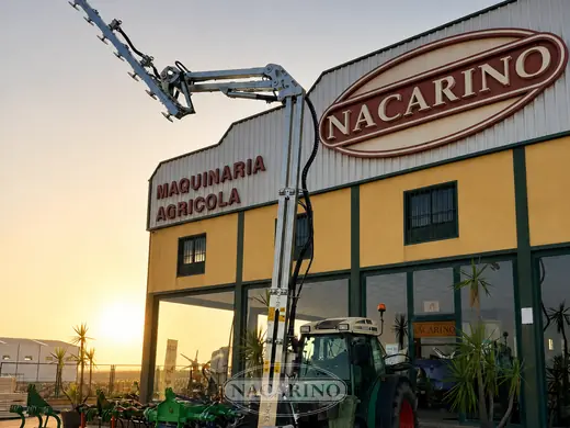 Tractor con barra de poda articulada delante de la nave de Nacarino en Aceuchal