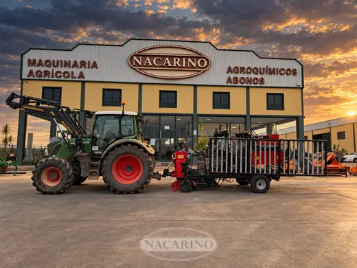 Tractor con vibrador de paraguas plegado, delante de la nave de Nacarino al atardecer