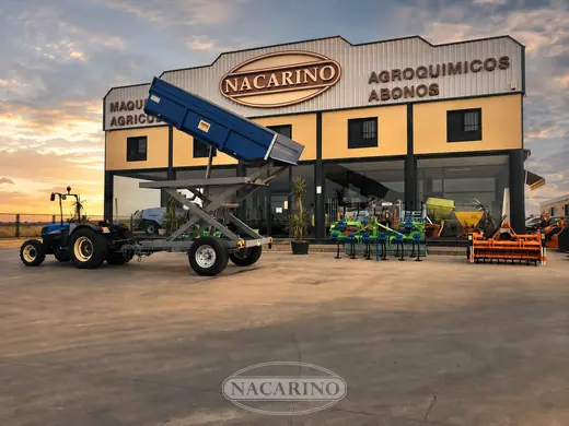 Remolque azul con tolva elevada y tractor en la campa de exposición de Nacarino