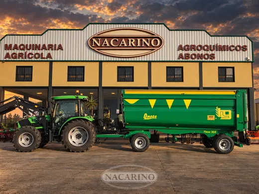 Remolque basculante verde enganchado a un tractor delante de la nave de Nacarino en Aceuchal