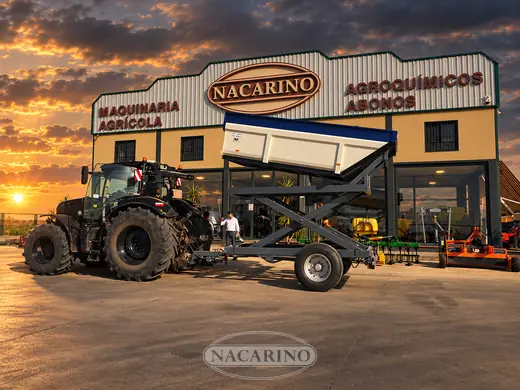 Remolque elevador de tijera con la caja elevada y tractor, delante de la nave de Nacarino al atardecer