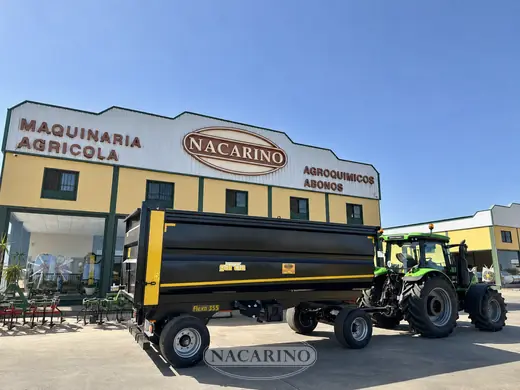 Bañera basculante negra y amarilla con tractor delante de la nave de Nacarino en Aceuchal