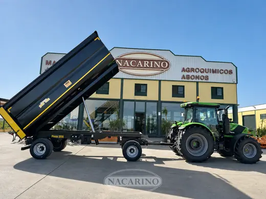 Bañera basculante volcada junto a un tractor delante de la nave de Nacarino en Aceuchal