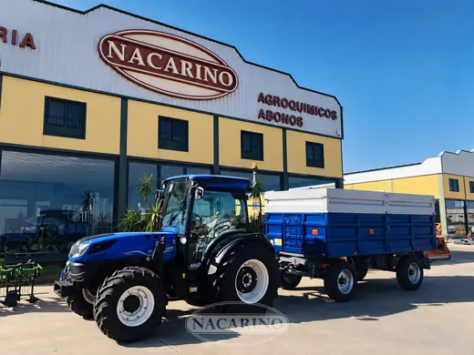 Tractor azul con remolque azul delante de la nave de Nacarino en Aceuchal