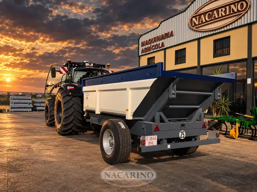 Tractor con bañera negra basculada delante de la nave de Nacarino
