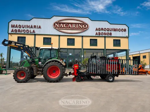 Tractor con remolque de barandillas cargado de maquinaria, delante de la nave de Nacarino en Aceuchal