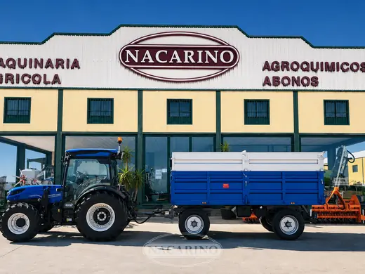 Tractor con remolque azul delante de la nave de Nacarino en Aceuchal