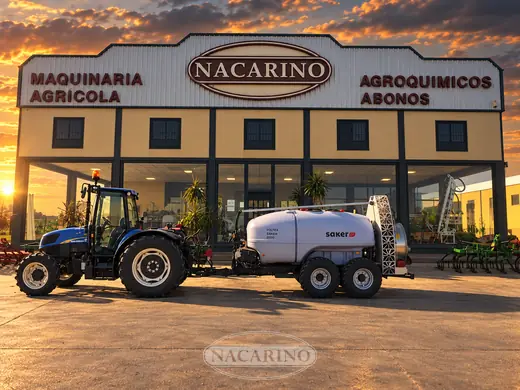 Tractor con pulverizador arrastrado y carrete, delante de la nave de Nacarino en Aceuchal